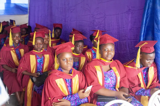 Graduands of Sunset Montessori School seated in maroon and gold gowns and mortarboards at the graduation ceremony